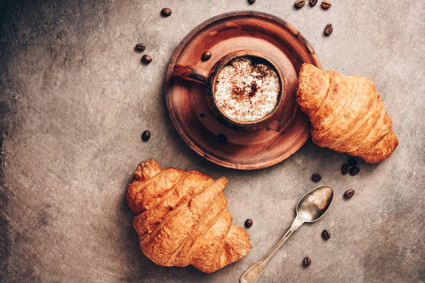 istock Fresh croissants and hot coffee in a vintage cup on a dark rustic textured background in brown colors. View from above, flat lay. 1177421886