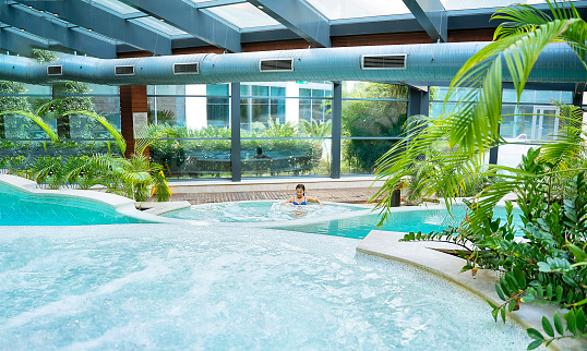 Asian woman in indoor hot tub, swimming pool enjoying holiday at hotel