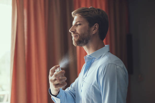 Serious young man preparing for his date Handsome young male perfuming himself in his bedroom perfume sprayer photos stock pictures, royalty-free photos & images