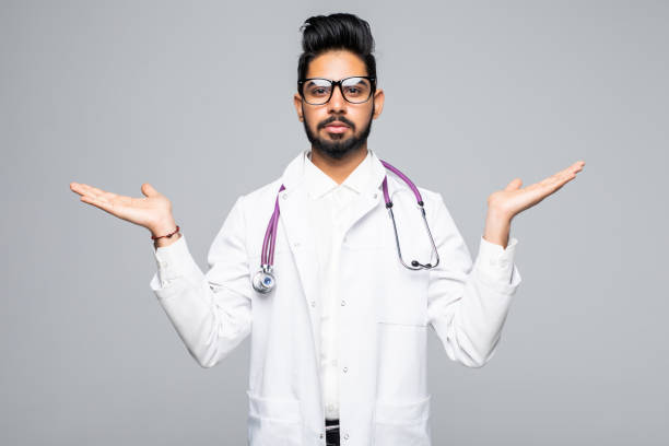 istock Smiling indian male doctor holding palms upwards as copyspace isolated on white background 1177426253