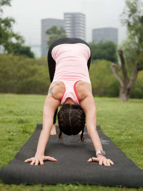 Young latin woman doing downward-facing dog yoga position outdoors latin woman, yoga, young adult, outdoors, fitness downward facing dog position stock pictures, royalty-free photos & images