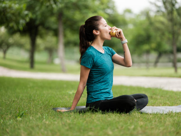 Young latin woman sitting outdoors and eating fruit