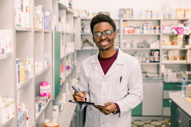 istock Smiling African American man pharmacist or Chemist Writing On Clipboard While standing in interior of pharmacy 1177433886