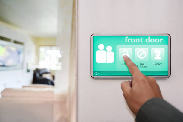 istock Home owner unlocking the front door of home, using a touchscreen device to control all the connected smart home features. 1177433896