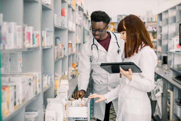 istock Portrait of two smiling friendly multiethnical pharmacists working in modern pharmacy and making order for medicines in distribution company 1177434241