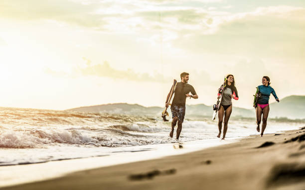 istock Happy young people running on a beach with surfboards. 1177436934