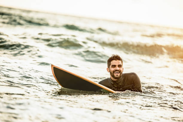 istock Happy young surfer floating in water on his board on sunset. 1177437626
