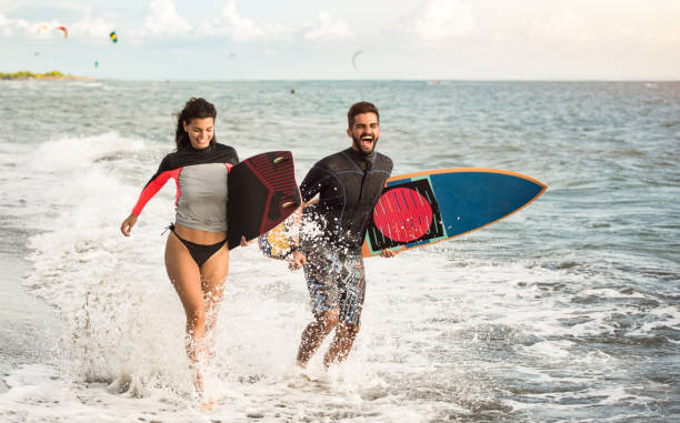 istock Happy young couple running on the beach with surfboards. 1177437830