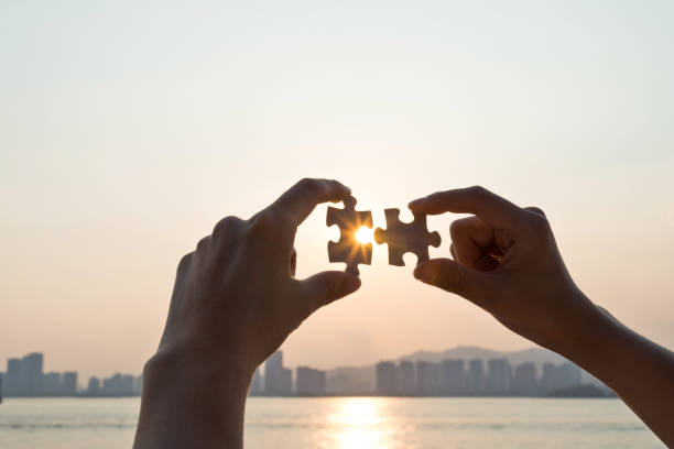 istock Woman hand putting puzzle pieces together in sunset 1177442661