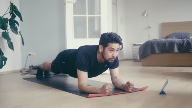 Asian man uses digital tablet to learn plank position