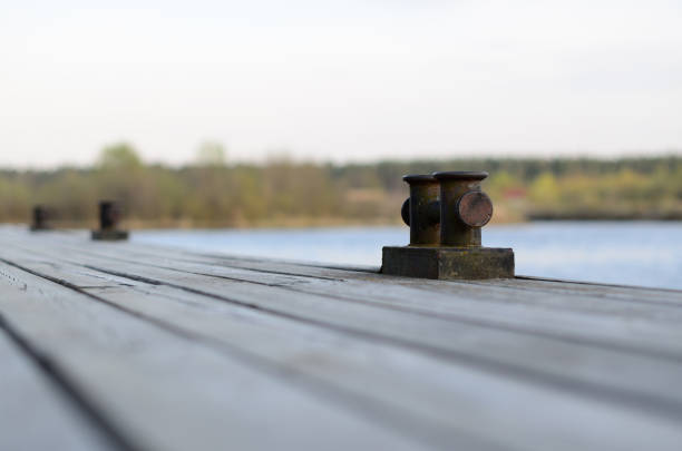 Cross bollard on wooden pier on summer day The cross bollard on a wooden pier on a summer day bollard pier water lake stock pictures, royalty-free photos & images