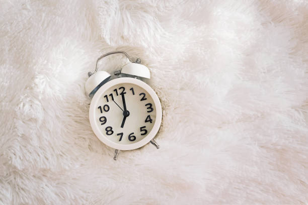 istock Retro alarm clock showing seven o'clock at the morning lying on the bed 1177448549