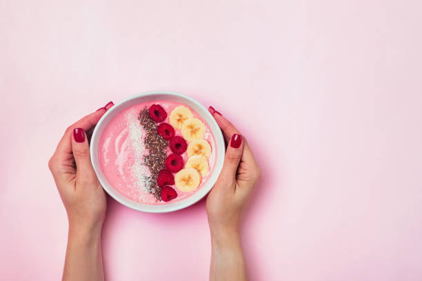 istock Woman's hands holsing a smoothie bowl with bananas and raspberies 1177448671