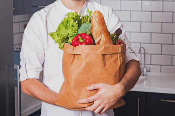 istock Man holding paper bag with different vegetable and other products 1177448801