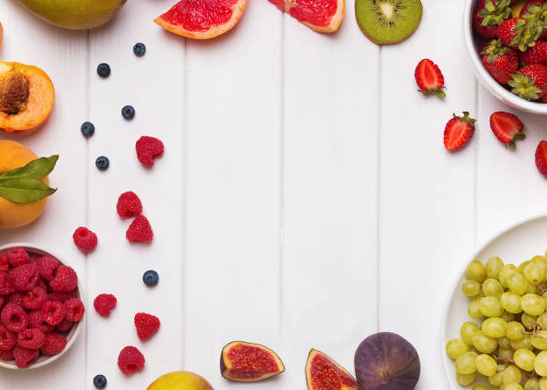 istock Fruits and berries arranged into frame on the white wooden background 1177448992