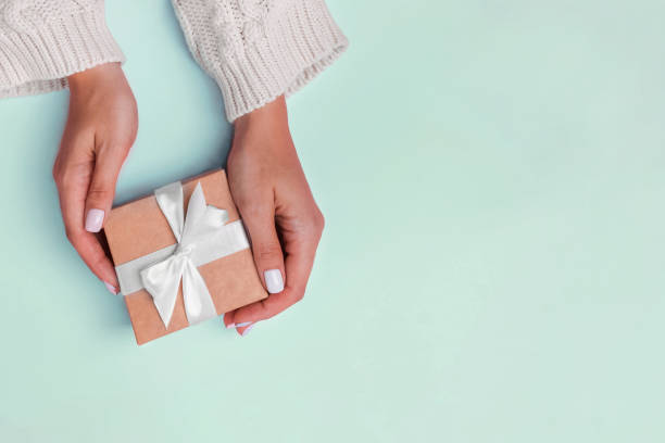 istock Woman's hands in knitted sweater holding a giftbox 1177449140