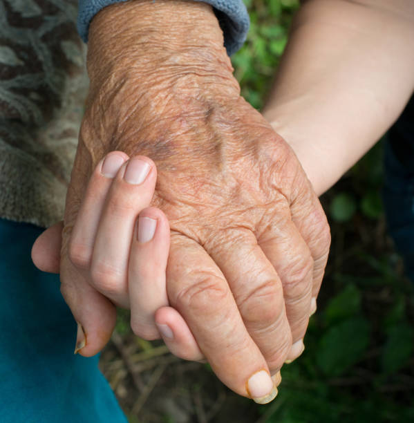istock Old and young woman holding hands together 1177453340