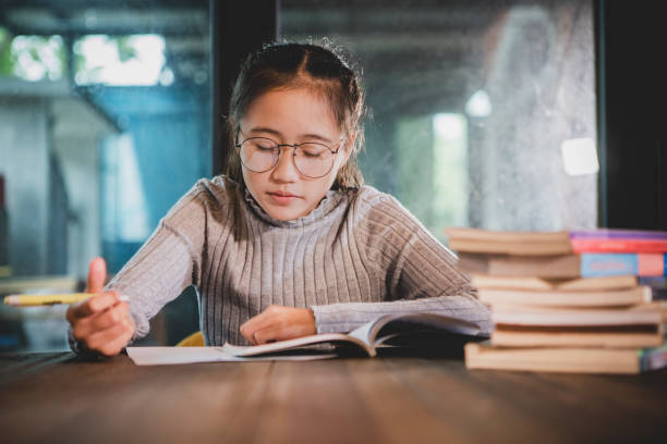 istock asian teenager doing school home work in library room 1177454815