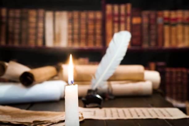 istock A lit candle against the background of blurred scrolls, books and bird feathers 1177458154