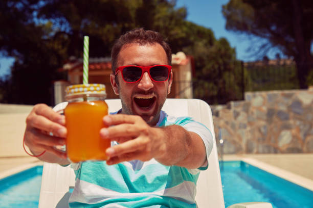 istock Attractive man drinking juice on the swimming pool. Summer concept. 1177458349