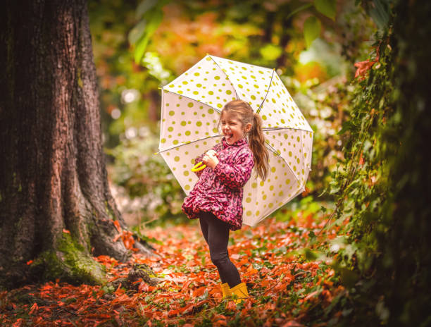 istock Happy child girl with an umbrella and rubber boots 1177458397