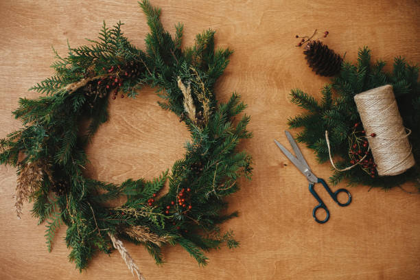 istock Christmas wreath workshop. Rustic Christmas wreath flat lay. Fir branches, pine cones, thread, berries, scissors on wooden table.  Authentic stylish still life. Happy Holidays 1177463159
