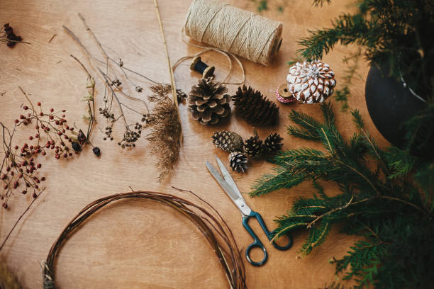 istock Making christmas wreath.Fir branches, pine cones, thread, scissors, wooden circle, berries and herbs for rustic wreath on wooden table. Details for workshop of making christmas wreath 1177463252