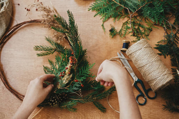 istock Hands holding fir branches and pine cones, berries, thread, scissors on wooden table. Making rustic christmas wreath flat lay. Details for  christmas wreath workshop 1177464665