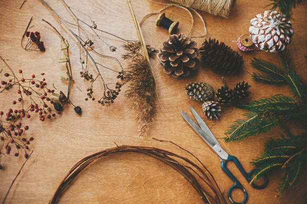 istock Details for workshop of making christmas wreath. Fir branches, pine cones, thread, scissors, wooden circle, berries and herbs for rustic wreath on wooden table. Making christmas wreath 1177465437