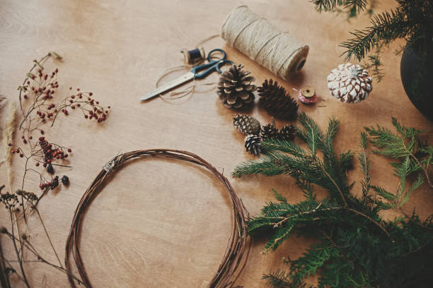 istock Making christmas wreath.Fir branches, pine cones, thread, scissors, wooden circle, berries and herbs for rustic wreath on wooden table. Details for workshop of making christmas wreath 1177465567