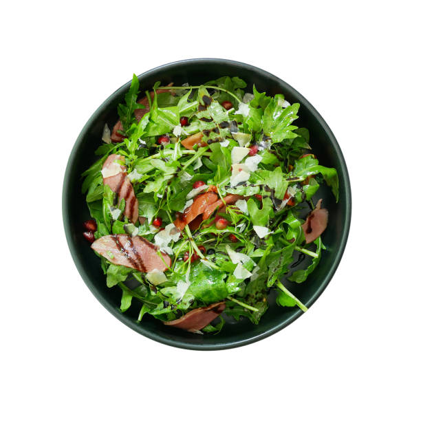 Top view of fresh green vegetable salad with sliced smoked duck and red pomegranate seeds and Parmesan cheese shaved in black bowl, healthy food dish isolated on white background with clipping path. Top view of fresh green vegetable salad with sliced smoked duck and red pomegranate seeds and Parmesan cheese shaved in black bowl, healthy food dish isolated on white background with clipping path. salad fruit lettuce spring stock pictures, royalty-free photos & images