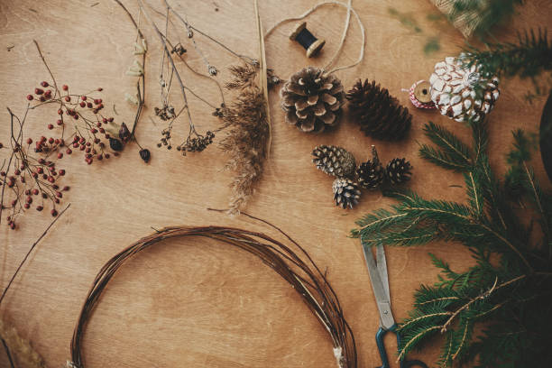 istock Details for workshop of making christmas wreath. Fir branches, pine cones, thread, scissors, wooden circle, berries and herbs for rustic wreath on wooden table. Making christmas wreath 1177466182