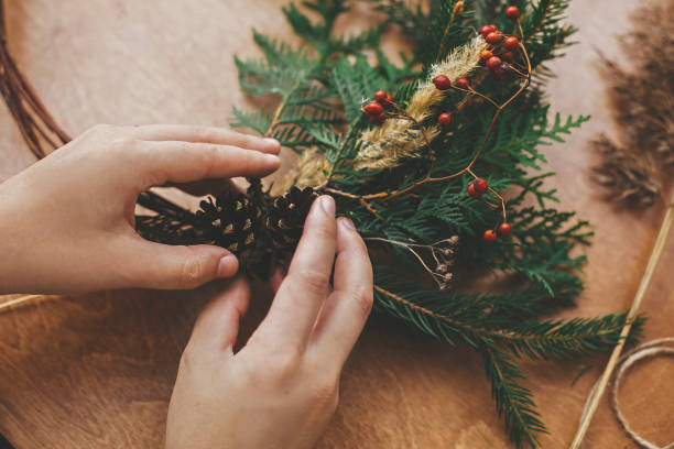 istock Hands holding pine cones, berries, fir branches, thread, scissors on wooden table.  Authentic rural wreath. Christmas wreath workshop. Making rustic christmas wreath. 1177466346