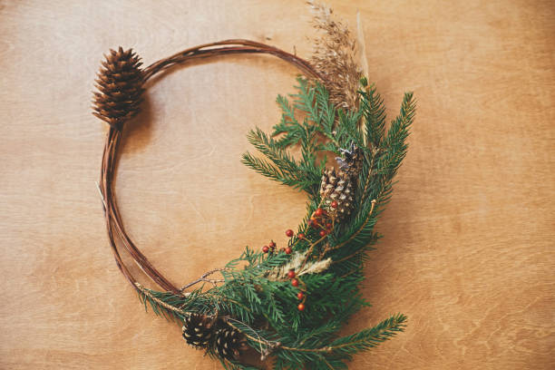 istock Creative rustic christmas wreath on wooden table. Christmas wreath with fir branches, berries, pine cones and herbs on rural background. Copy space. Seasons greetings 1177467869