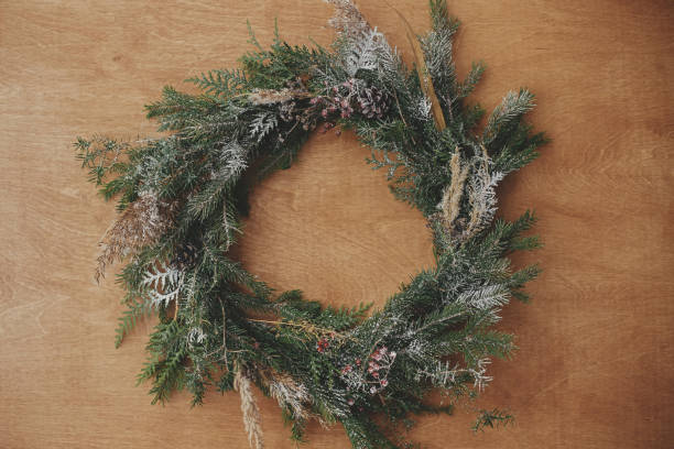 istock Christmas rustic wreath flat lay. Creative rural christmas wreath with fir branches, berries, pine cones and herbs on wooden table. Copy space. Seasons greetings 1177467931