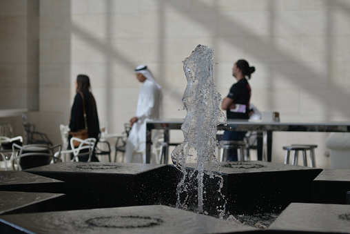 Doha, Qatar - May 21, 2016: Fountain and blurred background with a qatari couple at the Museum of islamic Art.