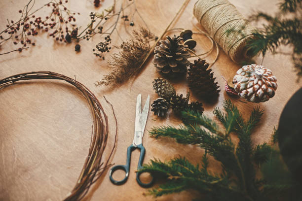 istock Details for workshop of making christmas wreath. Fir branches, pine cones, thread, scissors, wooden circle, berries and herbs for rustic wreath on wooden table. Making christmas wreath 1177469395