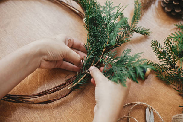 istock Hands holding cedar branches and pine cones, thread, scissors on wooden table. Details for workshop of making christmas wreath. Making rustic christmas wreath. 1177469842