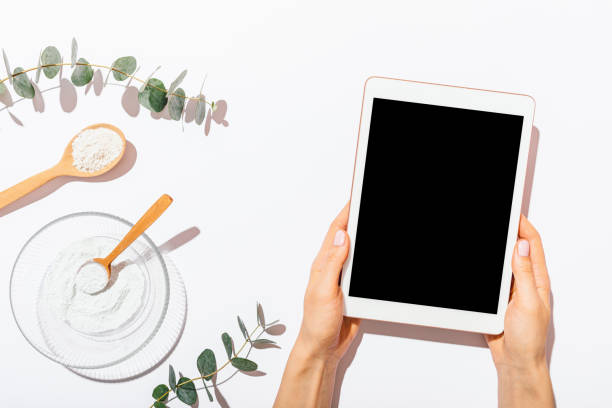 Flat layout female's hands holding blank-screen tablet