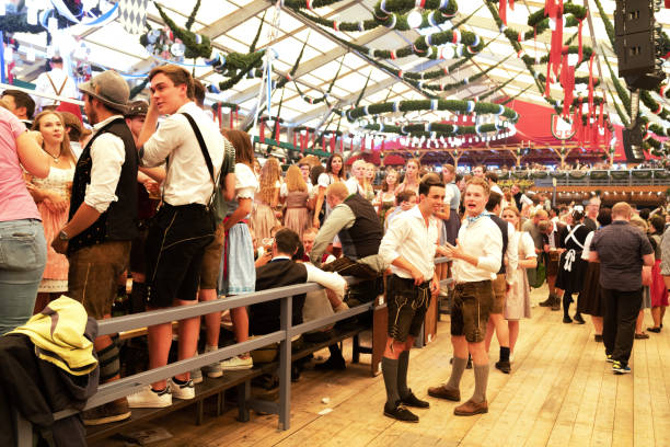 visitantes que comemoram oktoberfestfest na barraca da cerveja, munich, alemanha - lederhosen oktoberfest beer dancing - fotografias e filmes do acervo