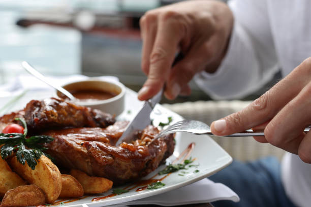 hombre almorzando de cerca, costillas de cerdo a la parrilla - carnivore fotografías e imágenes de stock