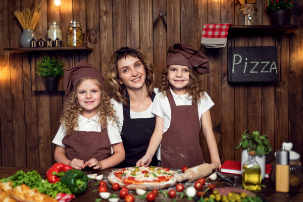 istock Mother with daughters cooking pizza in kitchen 1177485239