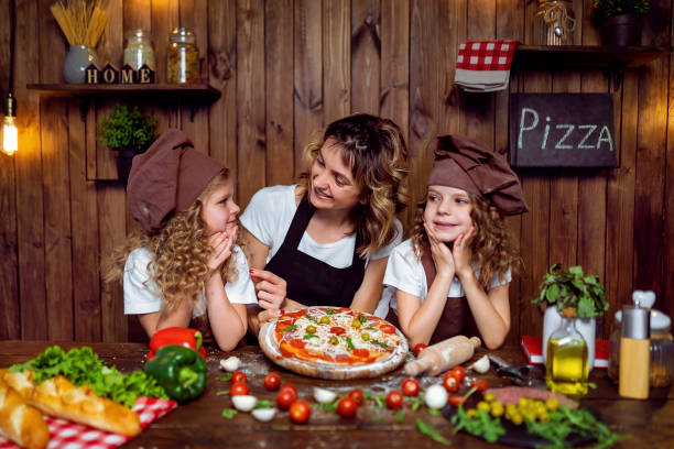 istock Mother with daughters cooking pizza in kitchen 1177485328