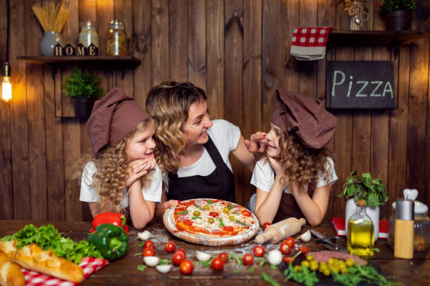 istock Mother with daughters cooking pizza in kitchen 1177485341