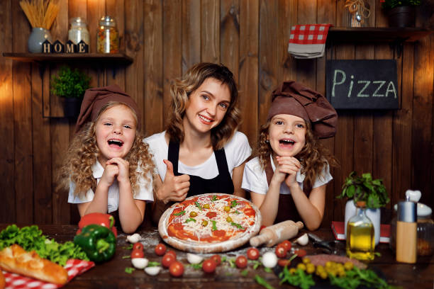 istock Mother with daughters cooking pizza in kitchen 1177485356