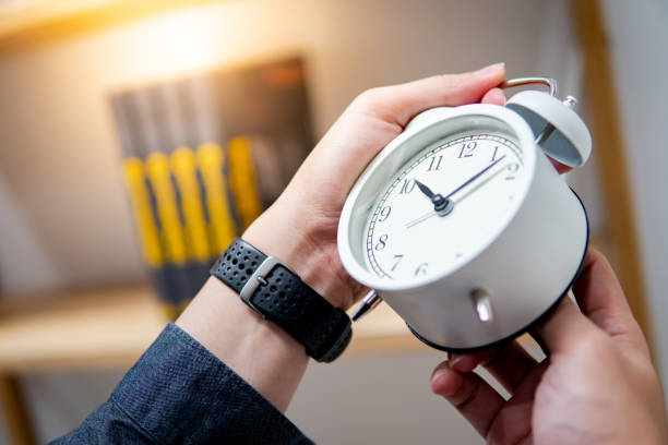 istock Male hand adjusting the time on white clock 1177485725