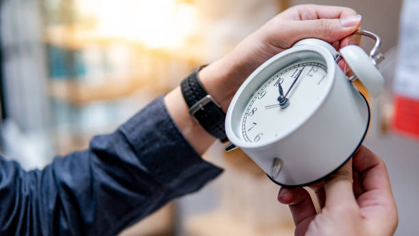 Male hand adjusting the time on white clock Male hand adjusting or changing the time on white clock. Time management concept. time zone stock pictures, royalty-free photos & images