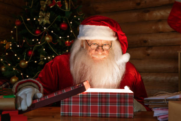 istock Happy Santa in costume and eyeglasses opening giftbox with magic light inside 1177491601
