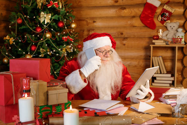 istock Serious Santa with touchpad and smartphone making online order for Christmas 1177491880