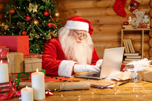 istock Santa Claus sitting by laptop while looking through xmas wishes in e-mail 1177491912